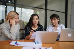 Three young business professionals standing together and discussing over business report