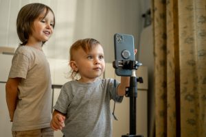 Two blogger brothers record videos on their phone using a tripod. Children and modern technologies